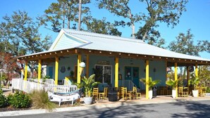 A building with a covered patio area, yellow pillars, and outdoor seating. - 1BR Oceanview at Carolinian, Pools, Amazing Views! (Myrtle Beach)