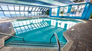 An indoor swimming pool with clear glass walls, a tiled floor, and a sign indicating a depth of 3 1/2 feet. - Pets welcome,direct oceanfront, poolside,1 bedroom (Myrtle Beach)