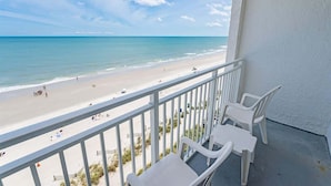 A balcony with white plastic chairs overlooking a beach. - Oceanfront View w/ Beach Access at Sea Mist Resort (Myrtle Beach)