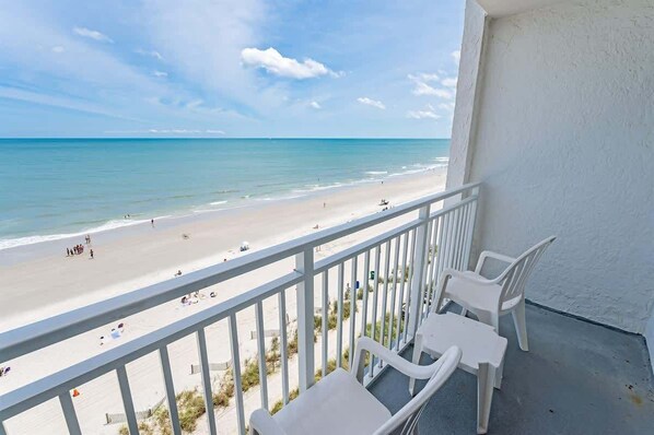 A balcony with white plastic chairs overlooking a beach. - Oceanfront View w/ Beach Access at Sea Mist Resort (Myrtle Beach)