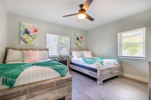 A bedroom with two beds, wooden headboards, and a ceiling fan.