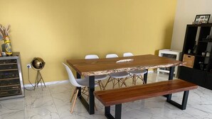 Un espace repas avec une table et des bancs en bois, des chaises blanches, un globe terrestre et une bibliothèque.