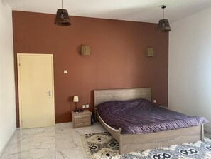 A bedroom with a wooden bed, a nightstand, a lamp, and a patterned rug.
