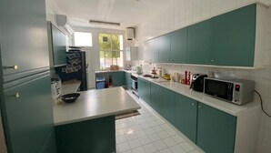 Une cuisine avec des meubles de couleur turquoise, un plan de travail blanc et un four à micro-ondes.