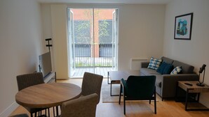 Een moderne woonkamer met een ronde houten tafel, twee fauteuils, een bank en een televisie.