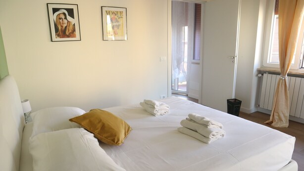 A hotel room with a bed, pillows, towels, and two framed pictures on the wall.