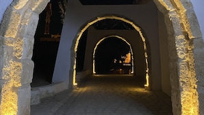 Une entrée en arc de pierre agrémentée d’un éclairage intégré, qui mène à un intérieur sombre.