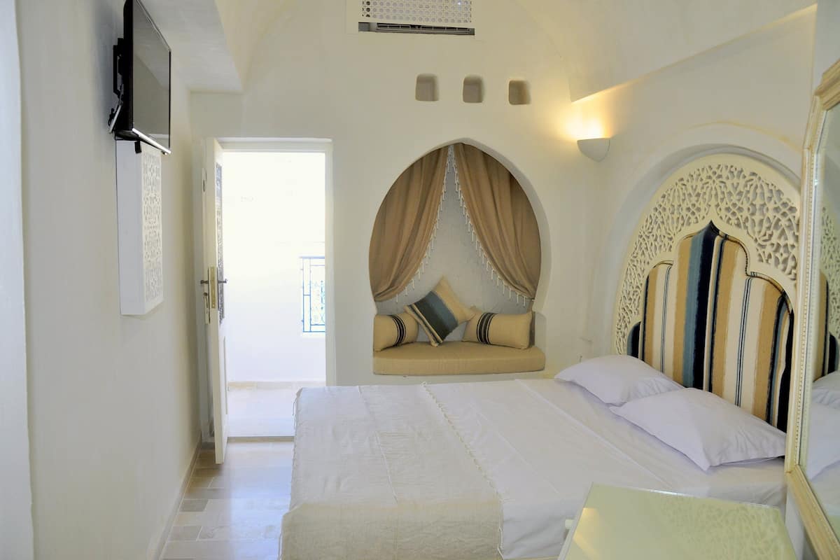 A bedroom with a large bed, a sofa bed, and a decorative arched headboard.