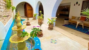 Une cour intérieure agrémentée d’une fontaine, de plantes en pot et d’un espace aménagé pour s’asseoir.