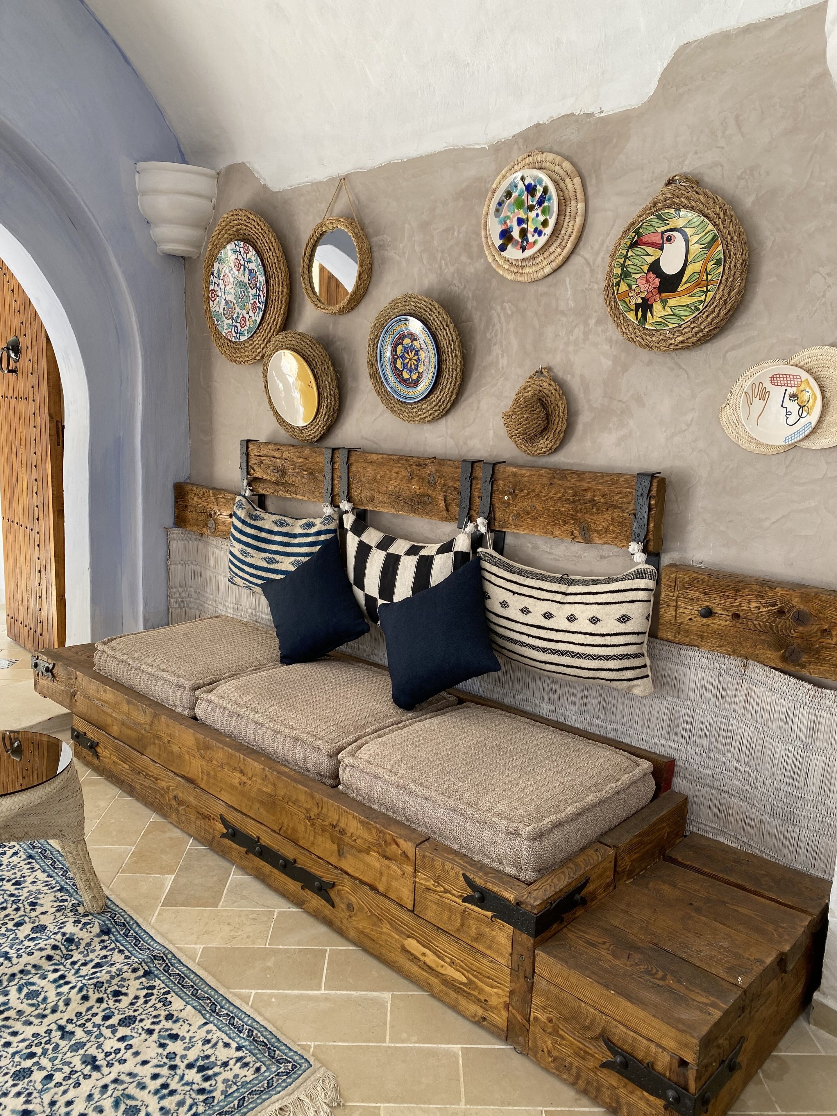 A cozy room with a wooden bed, woven wall decorations, and a patterned rug.