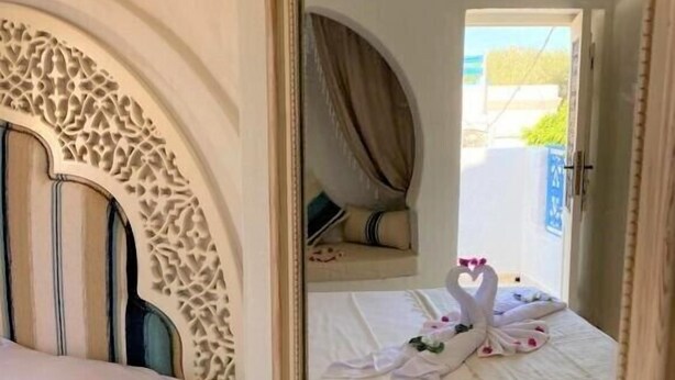Une chambre avec un lit, un grand miroir et une vue sur un balcon décoré d’un cygne.