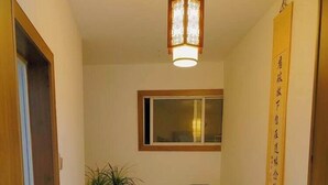 Ein Flur mit Esstisch und Stühlen, einem Blumentopf, einer Pendelleuchte und einem Fenster mit Aussicht.