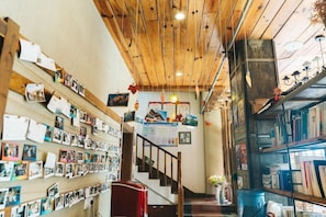 A cozy interior with wooden beams, a staircase, and shelves filled with books and photos.