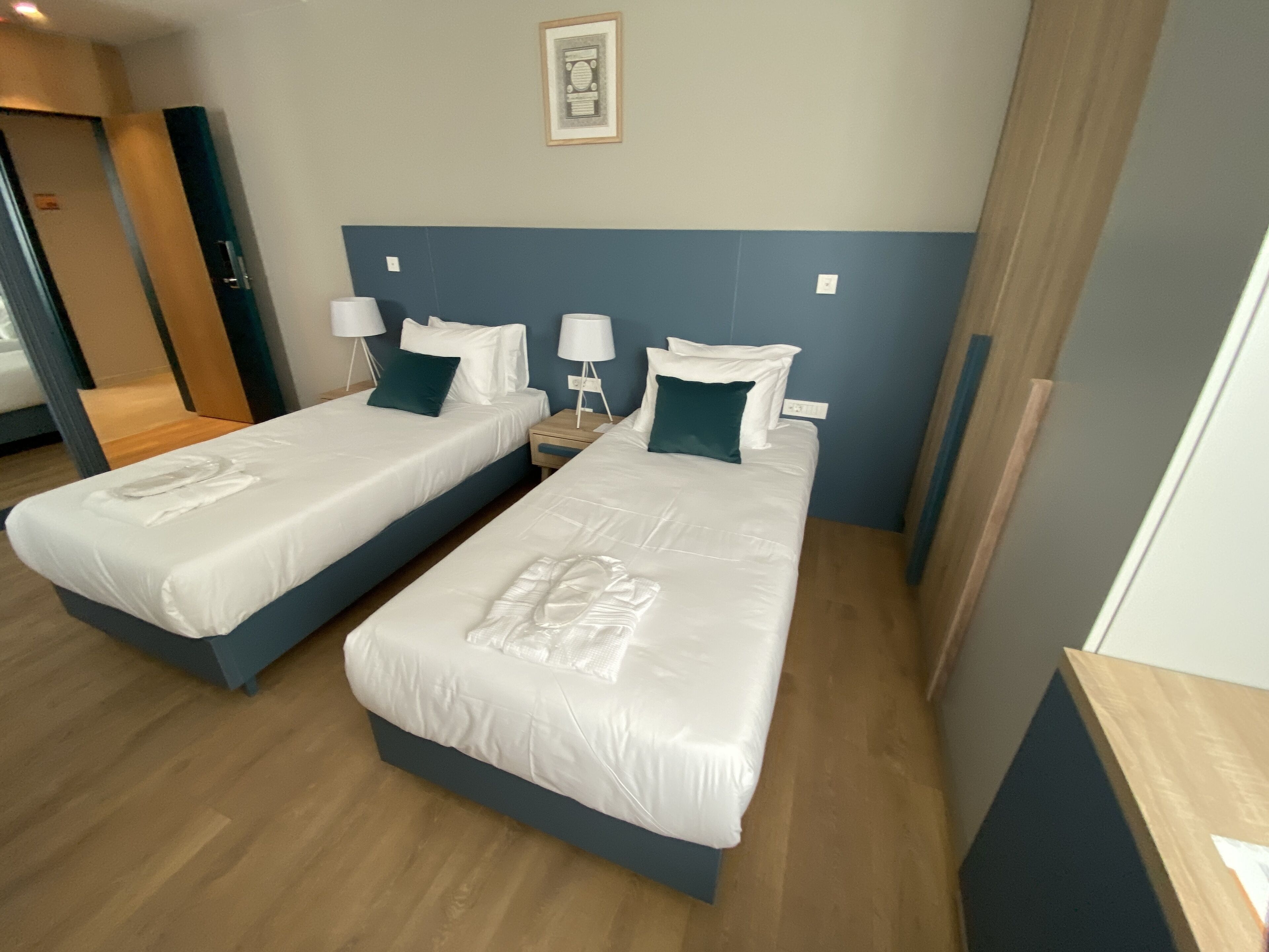 Two single beds with white linens, wooden headboards, and matching nightstands with lamps.