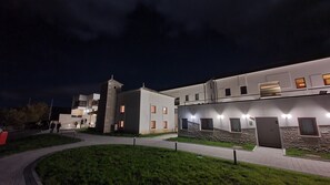 Un edificio moderno con varios niveles, una torre central y una entrada bien iluminada.