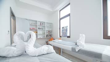 Una camera moderna e pulita con due letti, uno scaffale con articoli da toilette e una finestra.