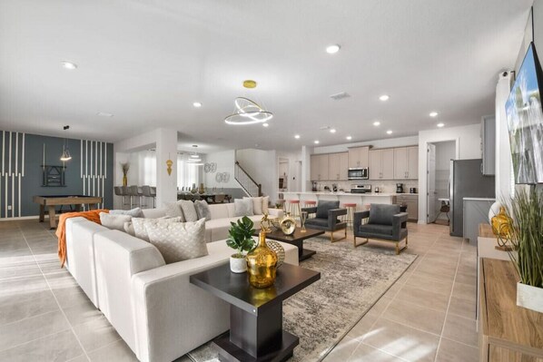 A spacious living area with a sofa, coffee table, and chairs, a kitchen with cabinets and appliances, and a dining area with a table and chairs.
