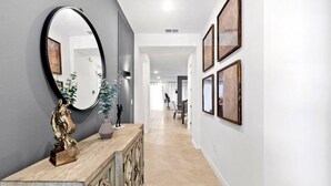 A hallway with a wooden console, a large mirror, and framed artwork on the walls.