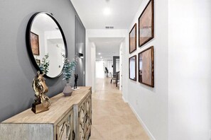 A hallway with a wooden console, a large mirror, and framed artwork on the walls.