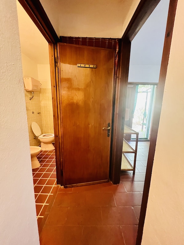 A wooden door leading to a bathroom with a toilet and a sink.