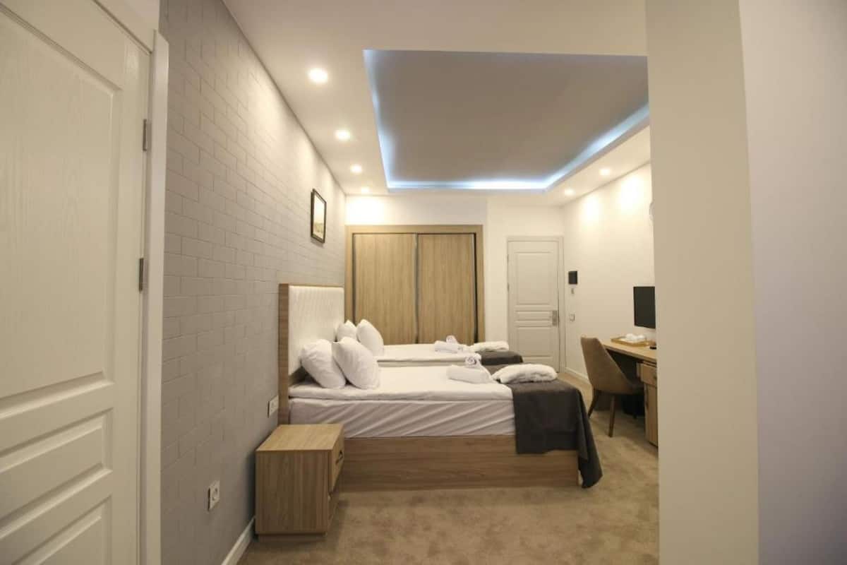 A modern bedroom with a bed, a desk, and a wardrobe.