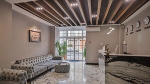 A lobby with a sofa, ottoman, and a reception desk. - ZAM-ZAM (Baku)