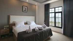 A hotel room with a large bed, a nightstand, a telephone, and a window with a view. - ZAM-ZAM (Baku)