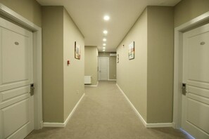 A hallway with beige walls, white doors, and a carpeted floor.