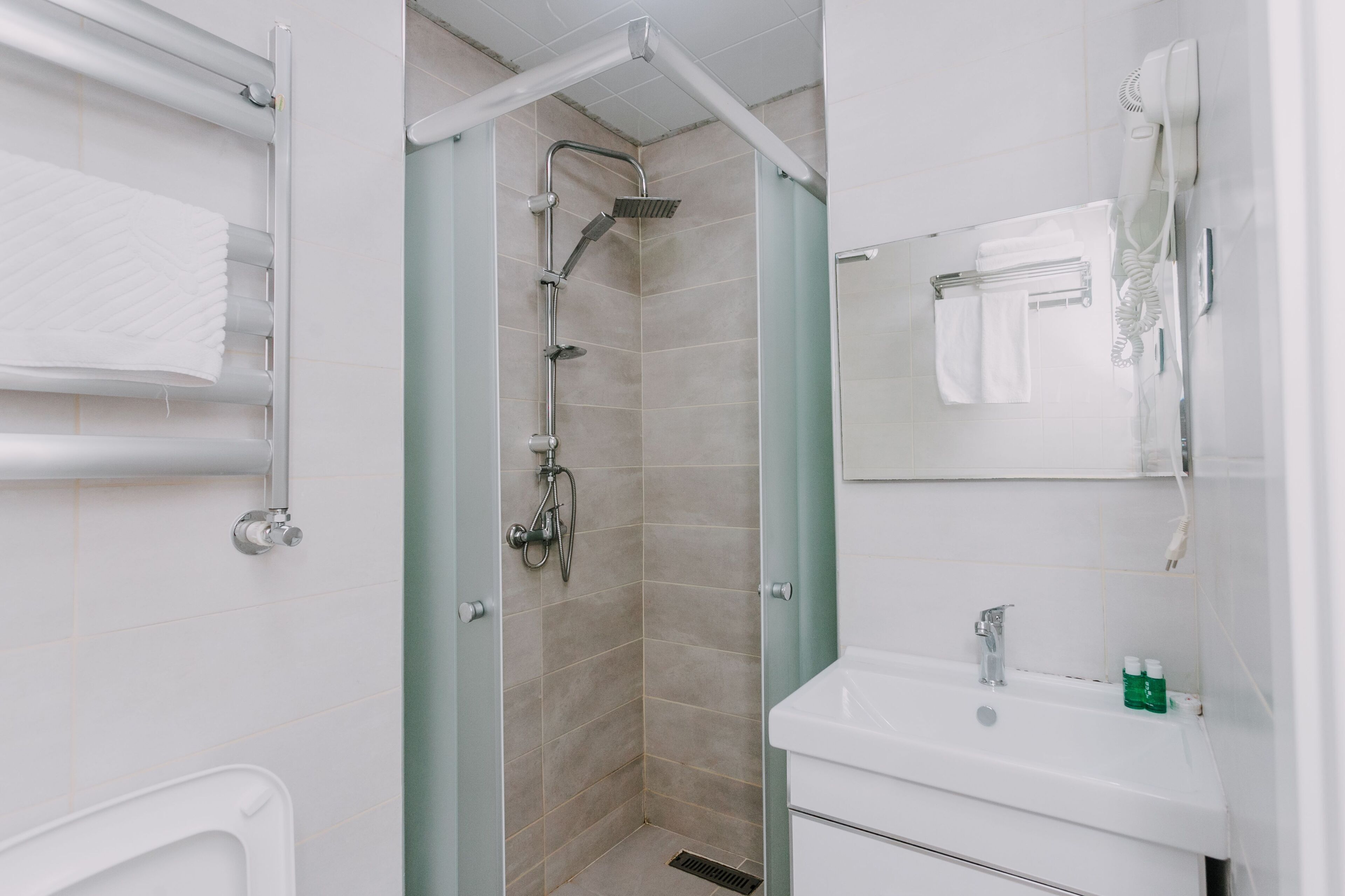 A modern bathroom with a glass-enclosed shower, a white sink, and a mirror above it.
