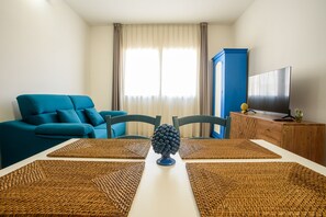 A living room with a blue sofa, two chairs, a coffee table, a TV, and a wooden cabinet.