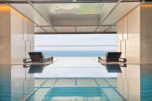 An infinity pool with two lounge chairs facing a clear view of the sea. - Grand Hyams Hotel - Quy Nhon Beach (Quy Nhon)