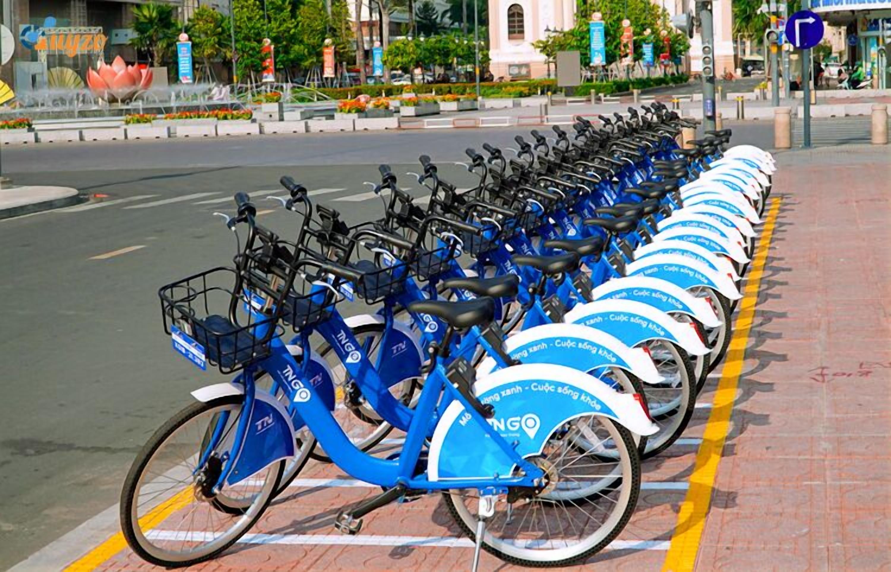 A row of blue bicycles parked on a sidewalk.