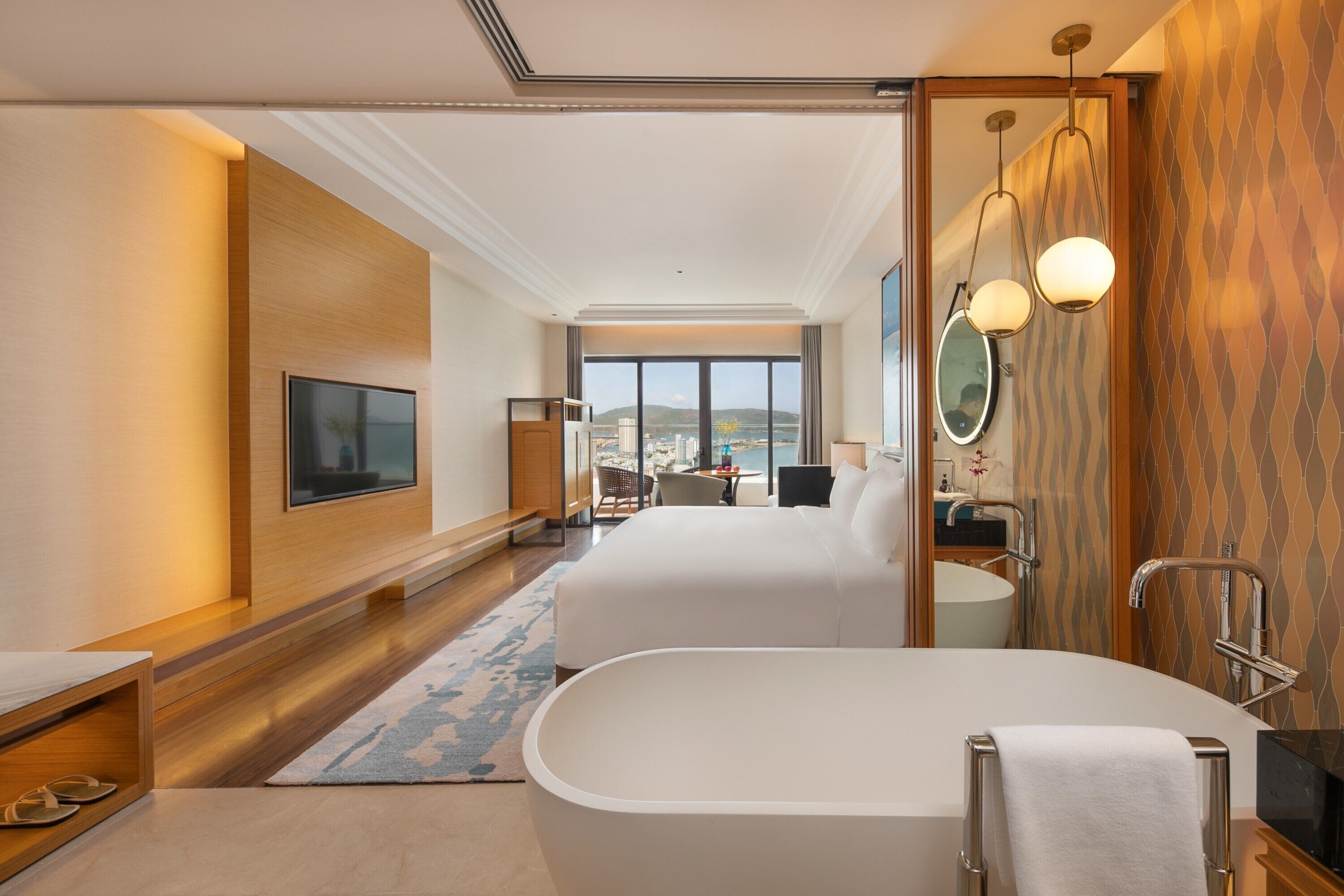 Une chambre d’hôtel avec un grand lit, une salle de bain séparée avec une baignoire, une télévision et une vue sur la ville.
