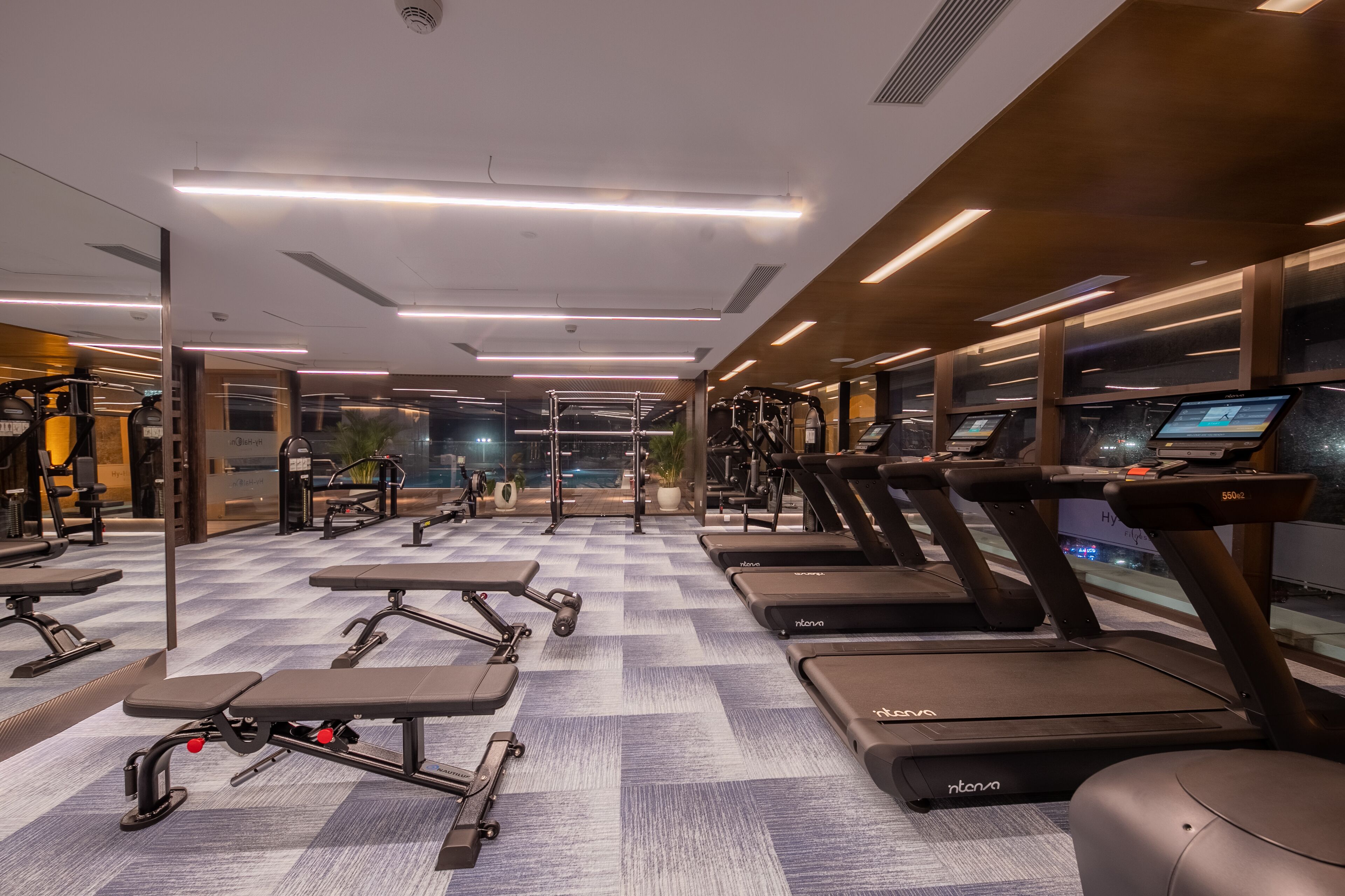 Ein Fitnessstudio mit Laufbändern, Kraftgeräten und Bänken.