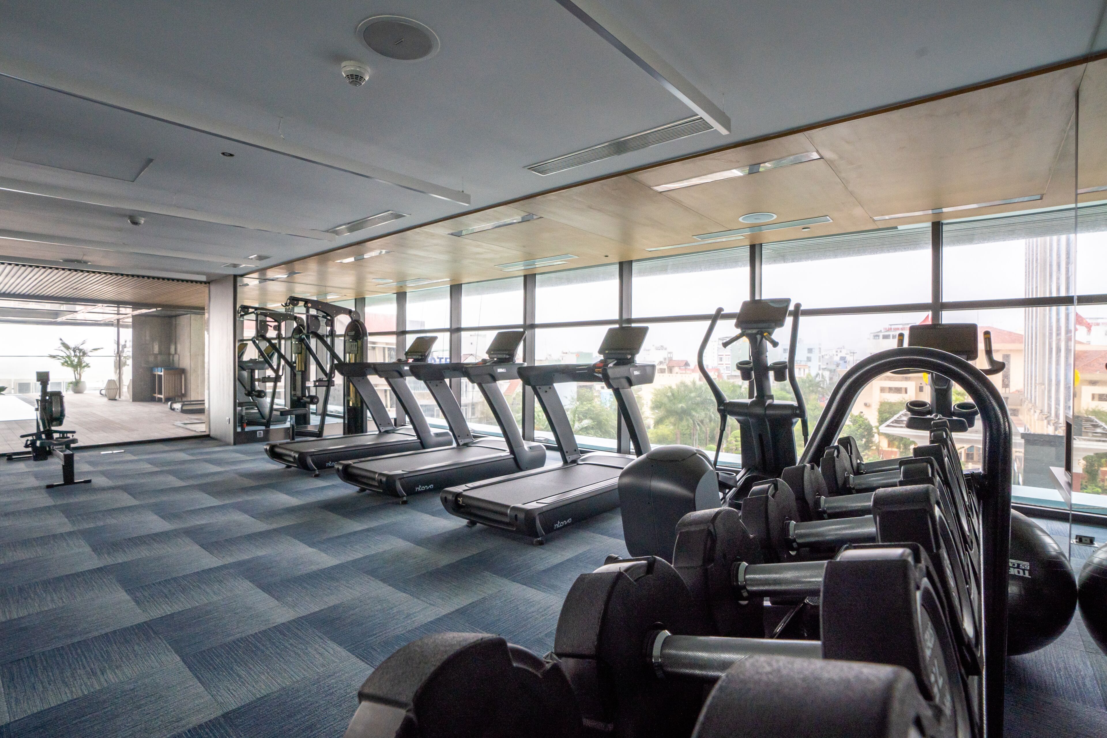 Une salle de sport équipée de tapis de course, d'appareils de musculation et d'autres équipements d'exercice.