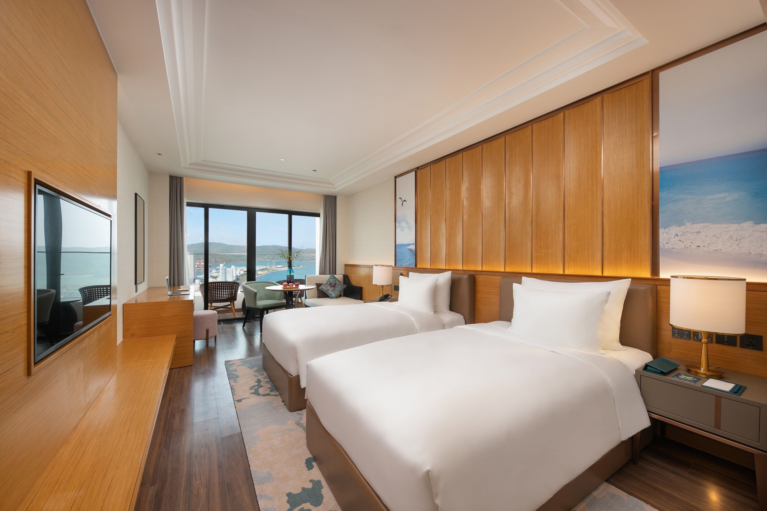 Hotelkamer met twee bedden, een bureau, een stoel en uitzicht op de stad, met een groot raam.