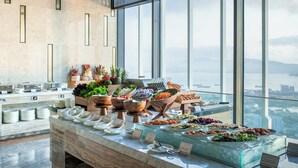 Un bufé con diversos alimentos y vistas a la ciudad a través de amplias ventanas.