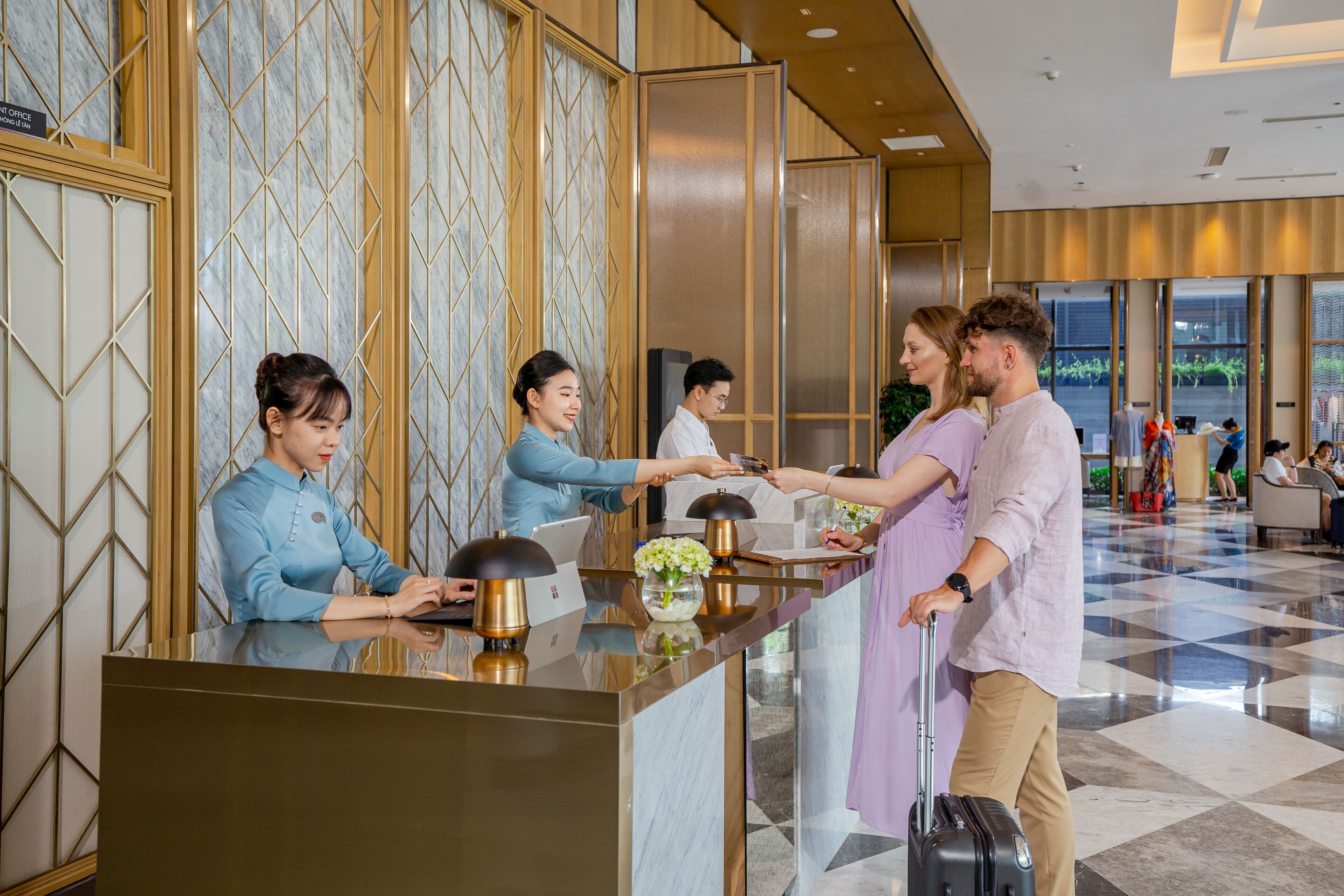 A hotel reception desk with staff members attending to guests.