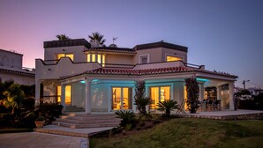 A modern two-story house with a patio area and a covered outdoor seating space. - Oceanfront Villa with three bedrooms plus one (Lagoa)