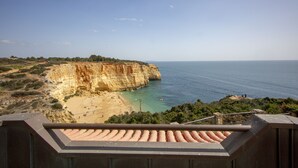 A coastal cliff with a beach, clear blue sea, and a view from a terrace. - Oceanfront Villa with three bedrooms plus one (Lagoa)