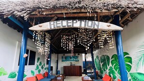 A reception area with a thatched roof, wooden furniture, and a wall mural. - Nungwi Beach Front (Nungwi)
