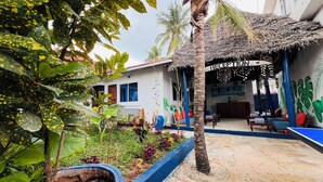 A reception area with a thatched roof, a reception desk, and a seating area with blue cushions. - Nungwi Beach Front (Nungwi)