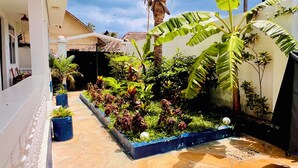 A courtyard with a tiled floor, potted plants, and a variety of greenery. - Nungwi Beach Front (Nungwi)