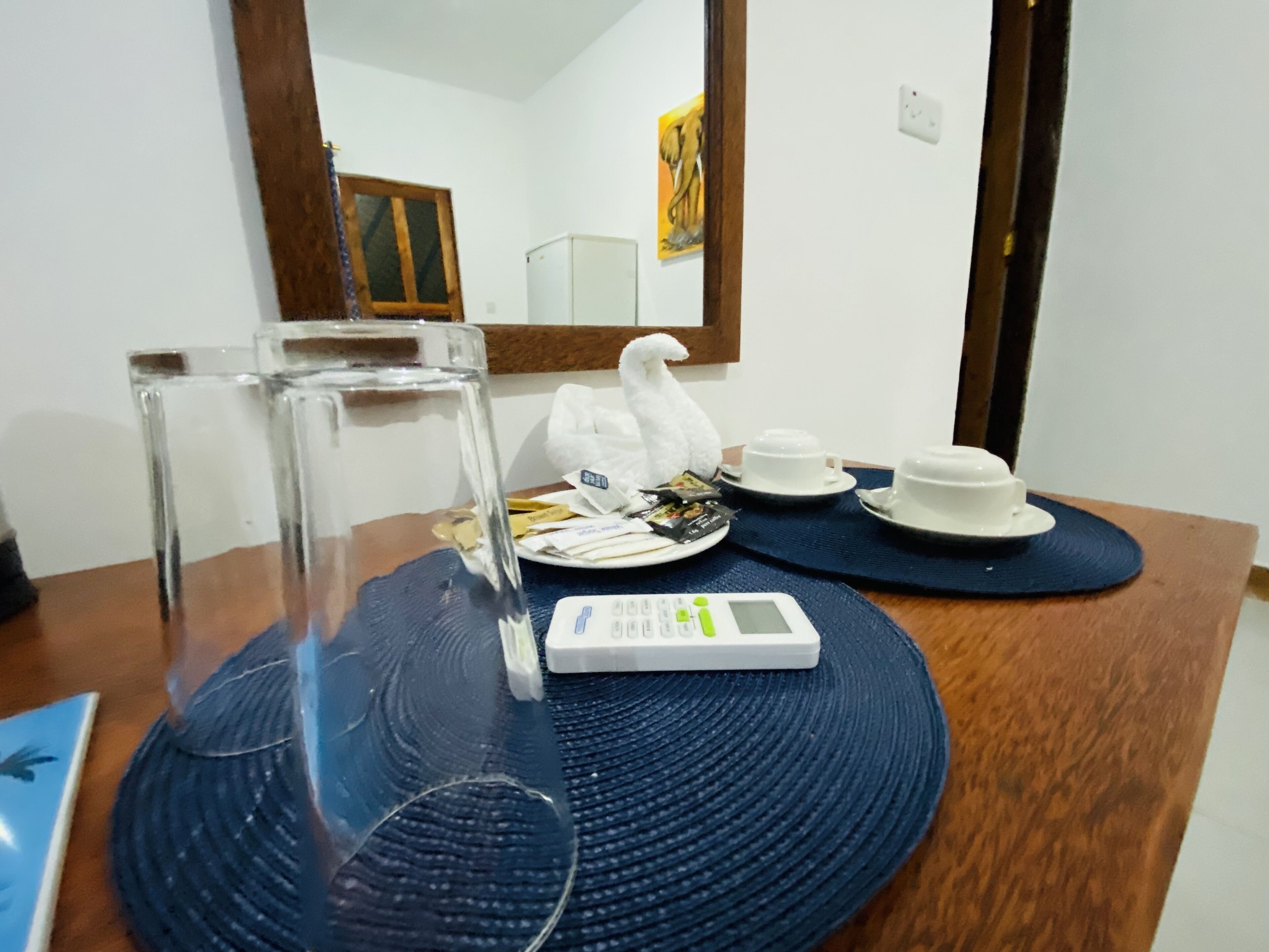 A dining table with a clear glass pitcher, white teapots, cups, and a digital scale.