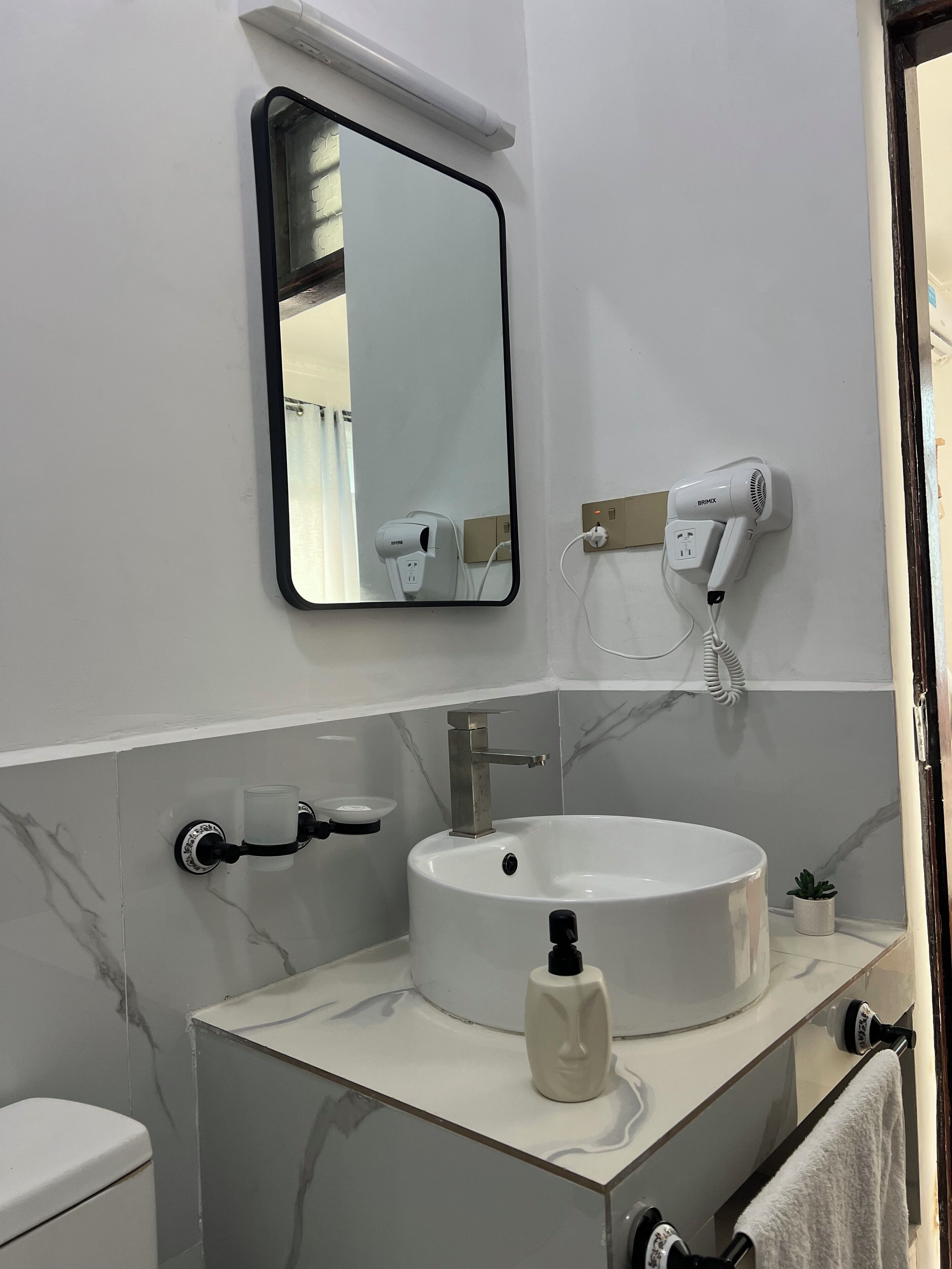 A bathroom with a white sink, a mirror, a hairdryer, and a towel rack.