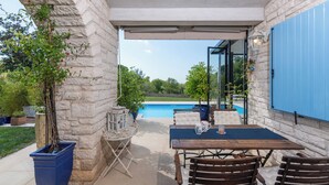 Eine Außenpatio mit Steinmauern, einem Pool und einem Tisch mit Stühlen.