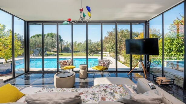 Ein modernes Wohnzimmer mit einer großen Glaswand, einem Pool und einem Flachbildfernseher.