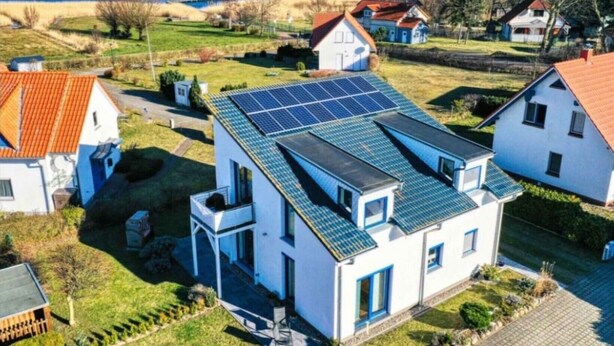 A residential building with a sloped roof, solar panels, and a small balcony. - Modern vacation home Bodden-Adler with direct water view (Fuhlendorf)