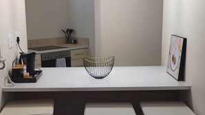 A modern kitchen with a white countertop, three pendant lights, and two white stools. - Effortless Homes (East London)