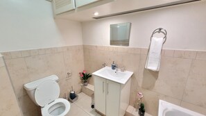 A bathroom with a toilet, sink, and bathtub. - Effortless Homes (East London)